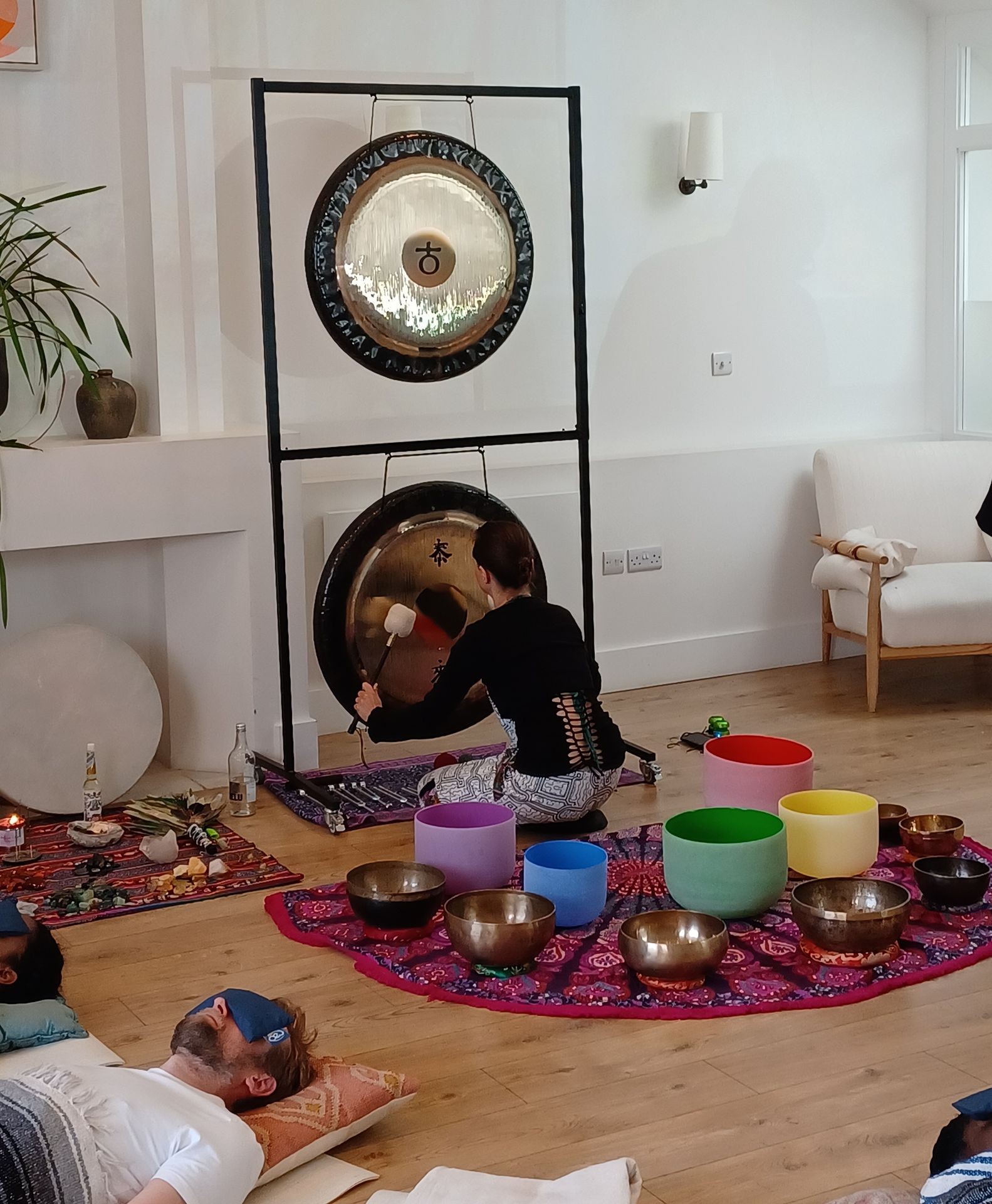 a woman playing a gong in a sound bath